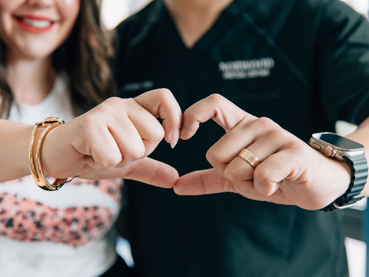 Two Norwood Dental Centre team members making a heart with their hands